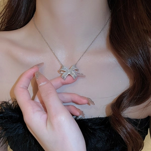 Elegant silver bow pendant necklace with sparkling cubic zirconia on a female model