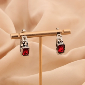 Detail of silver chain hoop earrings with a faceted red rectangle zircon on gold stand