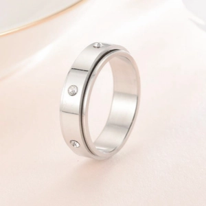Macro detail van zilveren spinner ring met drie ingelegde diamanten op zachte achtergrond
