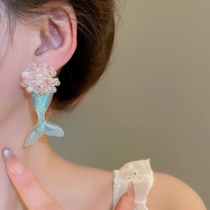 Detail view of pink resin flower cluster and blue fish tail earrings worn by model