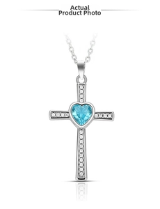 Macro detail of cross pendant with heart-shaped blue gemstone and sparkling zircon stones