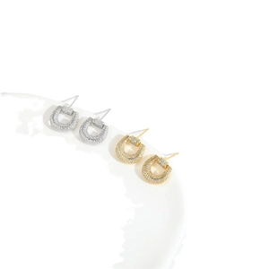 Minimalist horseshoe cross earrings with micro-pave cubic zirconia on a white plate