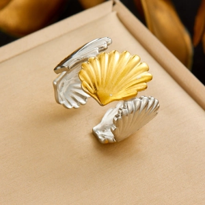 Detailed shot of two-tone gold and silver shell-shaped open ring on textured fabric