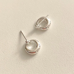 Minimalist 925 sterling silver hollow circular stud earrings on a textured off-white background