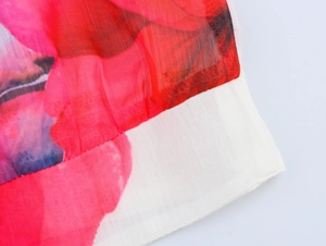 Macro view of floral chiffon fabric with red blossoms and delicate white edge stitching