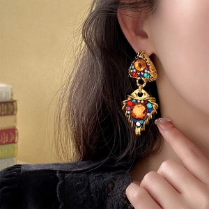Detail of vintage gold-tone drop earrings with colorful faux gemstones worn by a model