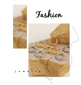 Close-up of twisted gold and silver hoop earrings on natural rock showing fine metal texture