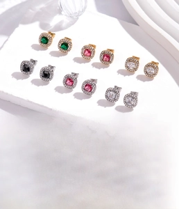 Détail de boucles d'oreilles géométriques en acier titane avec zircons de diverses couleurs