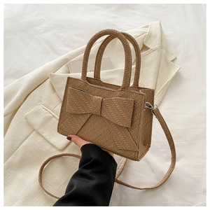 Detailed close-up of khaki woven handbag featuring a large bow and rounded top handle