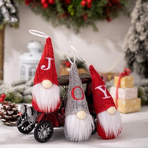 Three Christmas gnomes with JOY embroidered knitted hats displayed on a vintage red car