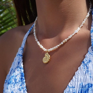 Detailed view of an 18k gold plated seashell pendant on a freshwater pearl necklace