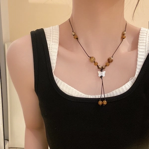 Detail of beaded necklace with silver butterfly pendant and amber stones on model
