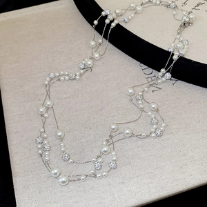 Elegant multi-layer pearl and rhinestone necklace with silver metal chain on fabric
