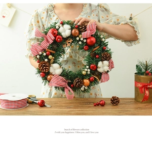Close-up of Christmas wreath with cotton, pine cones, and red checkered bow details