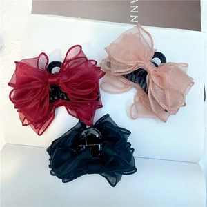 Close-up of organza bow hair claws in wine red, pink, and black on an open book
