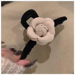 Close-up of velvet hair claw featuring a 3D camellia flower and elegant black clip
