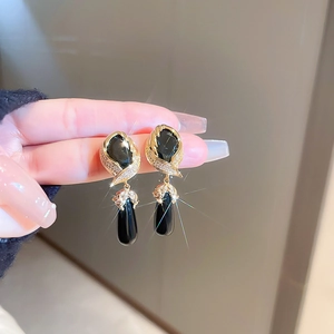 Detail of vintage gold earrings featuring black stones and sparkling leaf designs