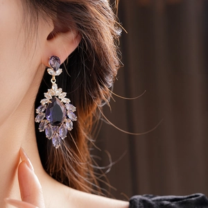 Gros plan de boucles d'oreilles en zircon violet foncé avec détails dorés élégants
