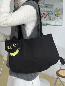 Cute black cat canvas tote bag with 3D tail and embroidery worn by model in a cafe