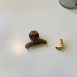 Détail macro d'une pince à cheveux translucide marron sur fond minimaliste blanc