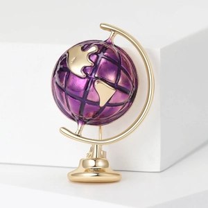 Detailed view of a gold globe brooch with purple enamel finish and golden continents