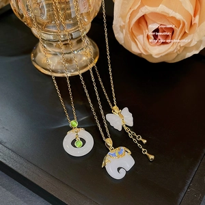 Close-up of titanium necklaces with green opal, elephant, and butterfly pendants