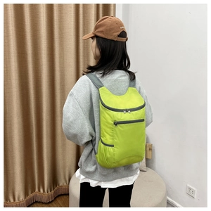 Detail of bright green lightweight folding backpack with grey breathable straps and zipper