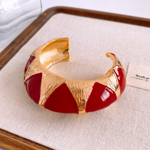 Detail of red and gold enamel open bangle featuring hammered texture and vintage patterns