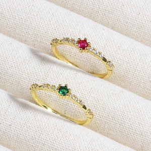 Macro shot of gold-plated rings with round emerald and ruby gemstones set with cubic zirconia