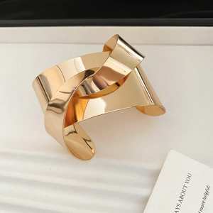 Close-up of golden wide cuff bracelet featuring a stylish knot design and mirror finish