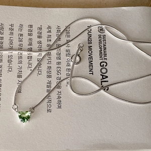 Detailed macro shot of a green heart zircon pendant on a silver snake chain necklace