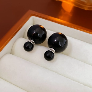 Detail of elegant double black pearl earrings set in a white velvet jewelry box