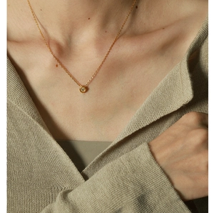 Macro detail of gold geometric circle pendant with cubic zirconia on a cable chain