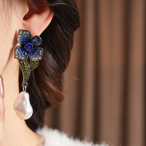 Gros plan de boucles d'oreilles vintage avec cristaux bleus et perle baroque sur mannequin