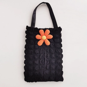 Close-up of black bubble textured car tissue holder with a vibrant orange floral accent