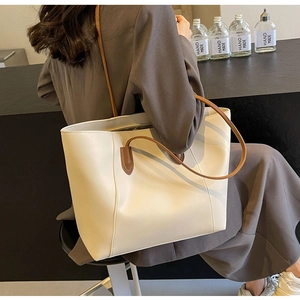 Model wearing a minimalist cream-colored large tote bag with brown straps for commuting