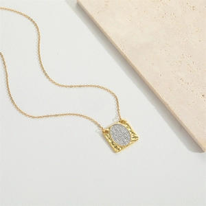Vintage gold necklace with square St. Benedict medal pendant on textured stone