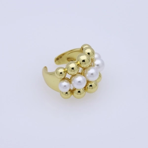 Close-up of golden ring featuring alternating white pearls and gold beads on a polished band
