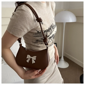 Brown leather underarm bag for women with a silver bow and knotted shoulder strap