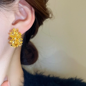 Detailed view of layered golden metallic flower stud earrings worn by a model