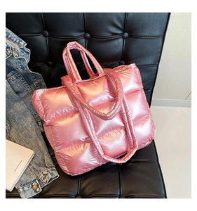 Dettaglio della borsa tote trapuntata rosa metallizzato con finitura lucida sul divano