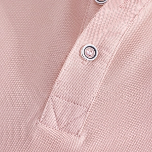 Close-up of pink pique polo shirt placket showing mesh fabric texture and neat stitching