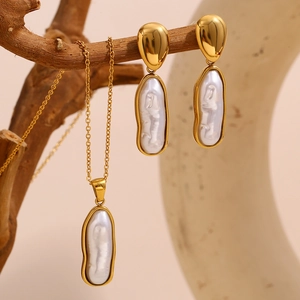 Parure collier et boucles d'oreilles en perles baroques dorées sur une branche