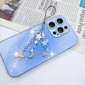 Detail of Y2K aesthetic phone charm with pink stars and metallic cross on blue case