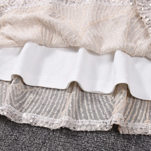 Gros plan d'une robe crème à paillettes avec couches de tulle et broderies détaillées