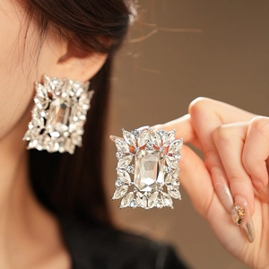 Detail of silver geometric earrings with a large rectangular crystal and zircon accents