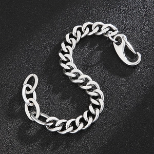 Gros plan d'une gourmette argentée avec fermoir mousqueton sur fond noir texturé