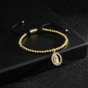 Detailed shot of gold Virgin Mary charm bracelet with micro-pave zircons on black rope