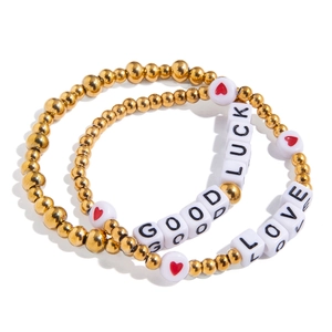 Set of two gold beaded bracelets with red heart motifs and GOOD LUCK LOVE letter charms