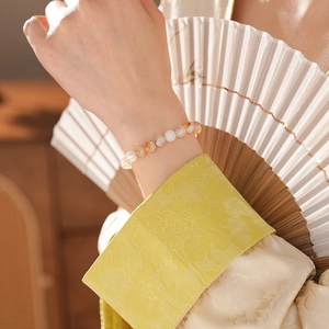 Bracelet en perles de quartz jaune porté au poignet au style vintage élégant